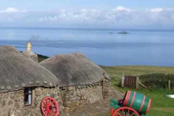 Ancient cottage with thatch roof overlooking the sea on the Isle of Skye